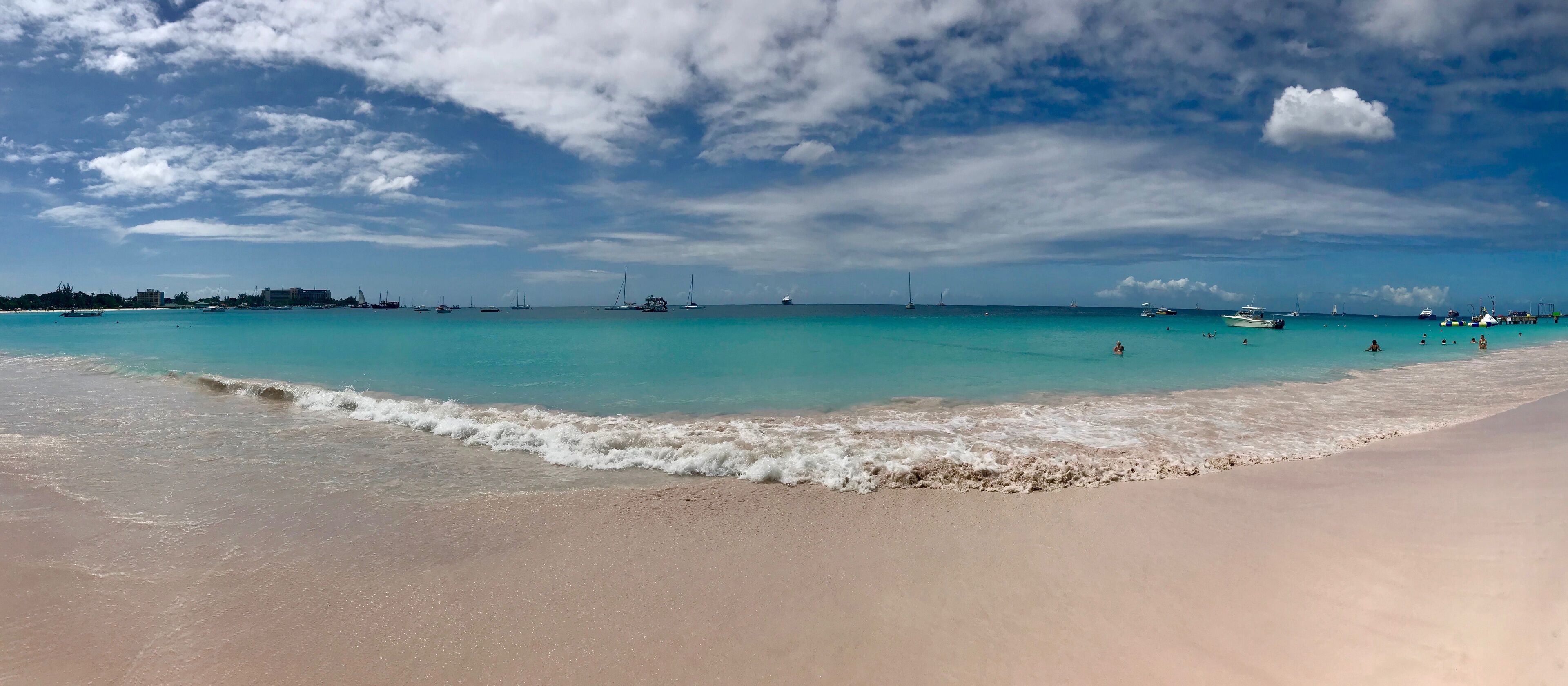 Panorama of a beautiful sunny day at Bayshore / Pebbles Beach (Carlisle Bay) near Bridgetown Barbados (Caribbean Island) - white sand, waves, blue sky with white clouds & sunshine