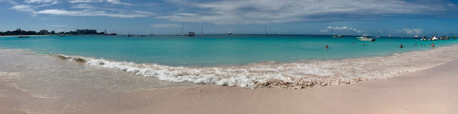 Panorama of a beautiful sunny day at Bayshore / Pebbles Beach (Carlisle Bay) near Bridgetown Barbados (Caribbean Island) - white sand, waves, blue sky with white clouds & sunshine