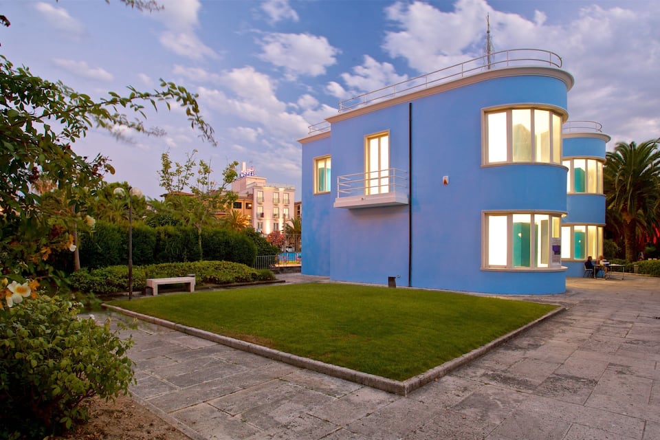 Un bâtiment moderne de couleur bleue, doté d’une pelouse bien entretenue et entouré de verdure.