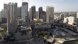 A cityscape with high-rise buildings, a central plaza, and a waterfront.