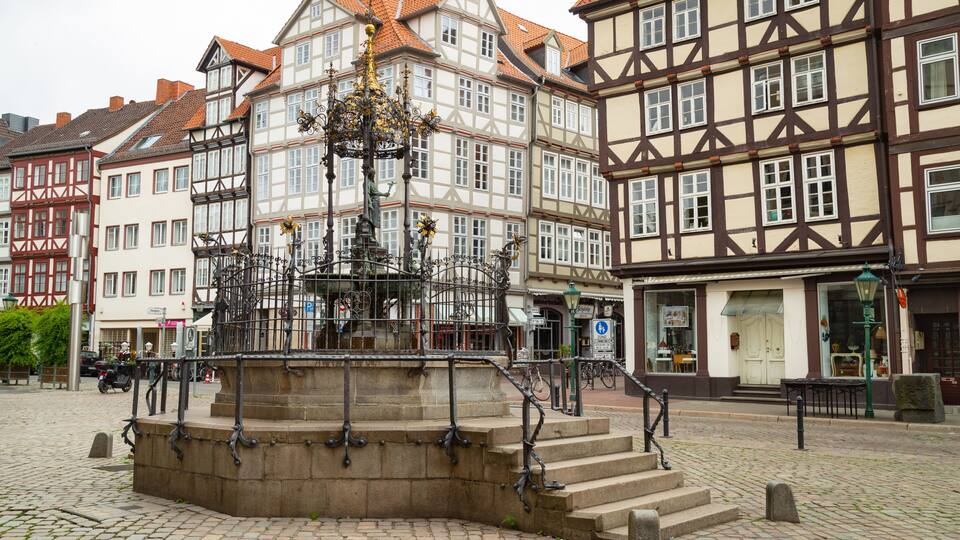 Ein historischer Platz mit einem zentralen Brunnen, Kopfsteinpflaster und traditionellen Fachwerkhäusern.
