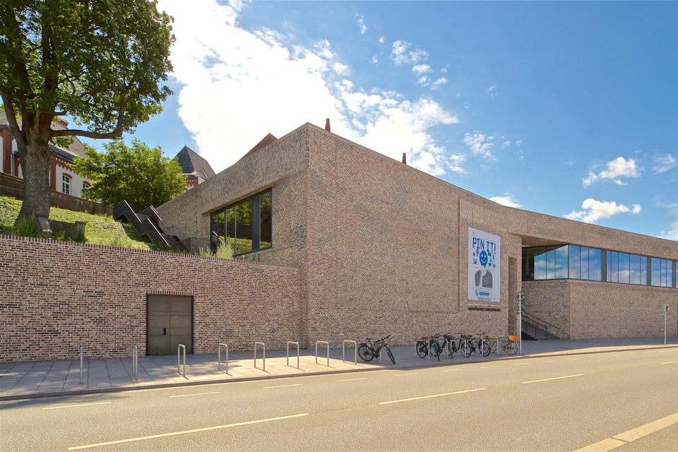 Un edificio moderno in mattoni con ampie finestre e un manifesto sulla facciata.