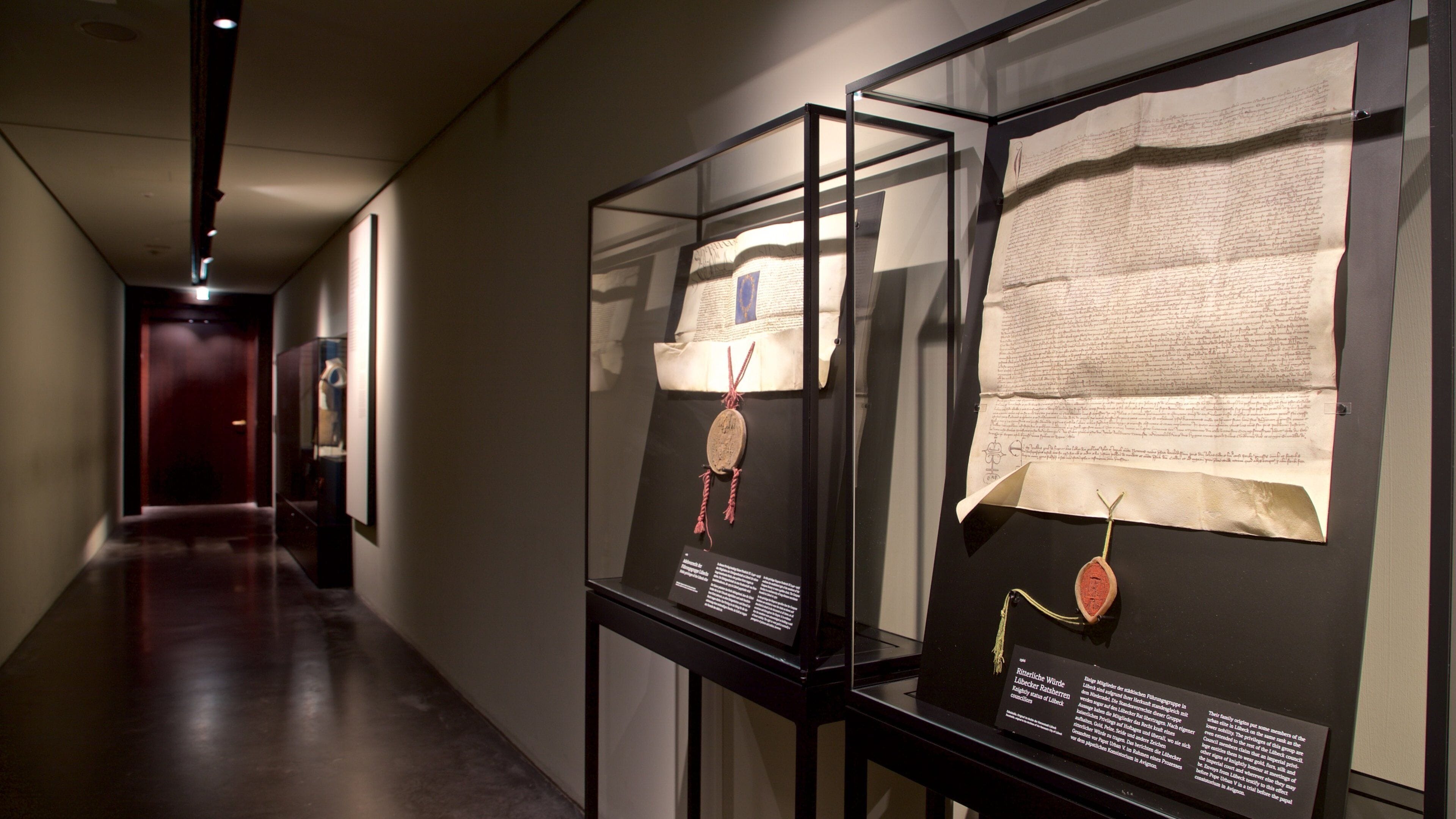 A museum exhibit with historical documents and artifacts displayed in glass cases.