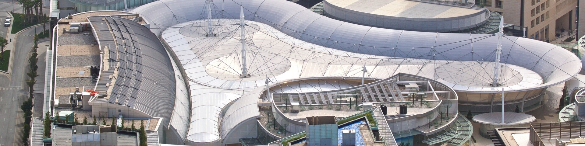 Un complejo arquitectónico moderno con estructuras curvas y una piscina central.