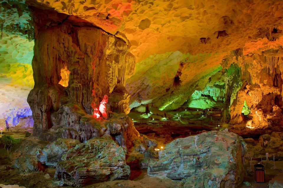 A cave with colorful lighting, stalactites, and stalagmites.