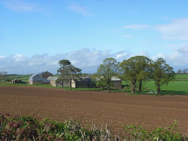 A rural landscape with a barn, a silo, and a plowed field.