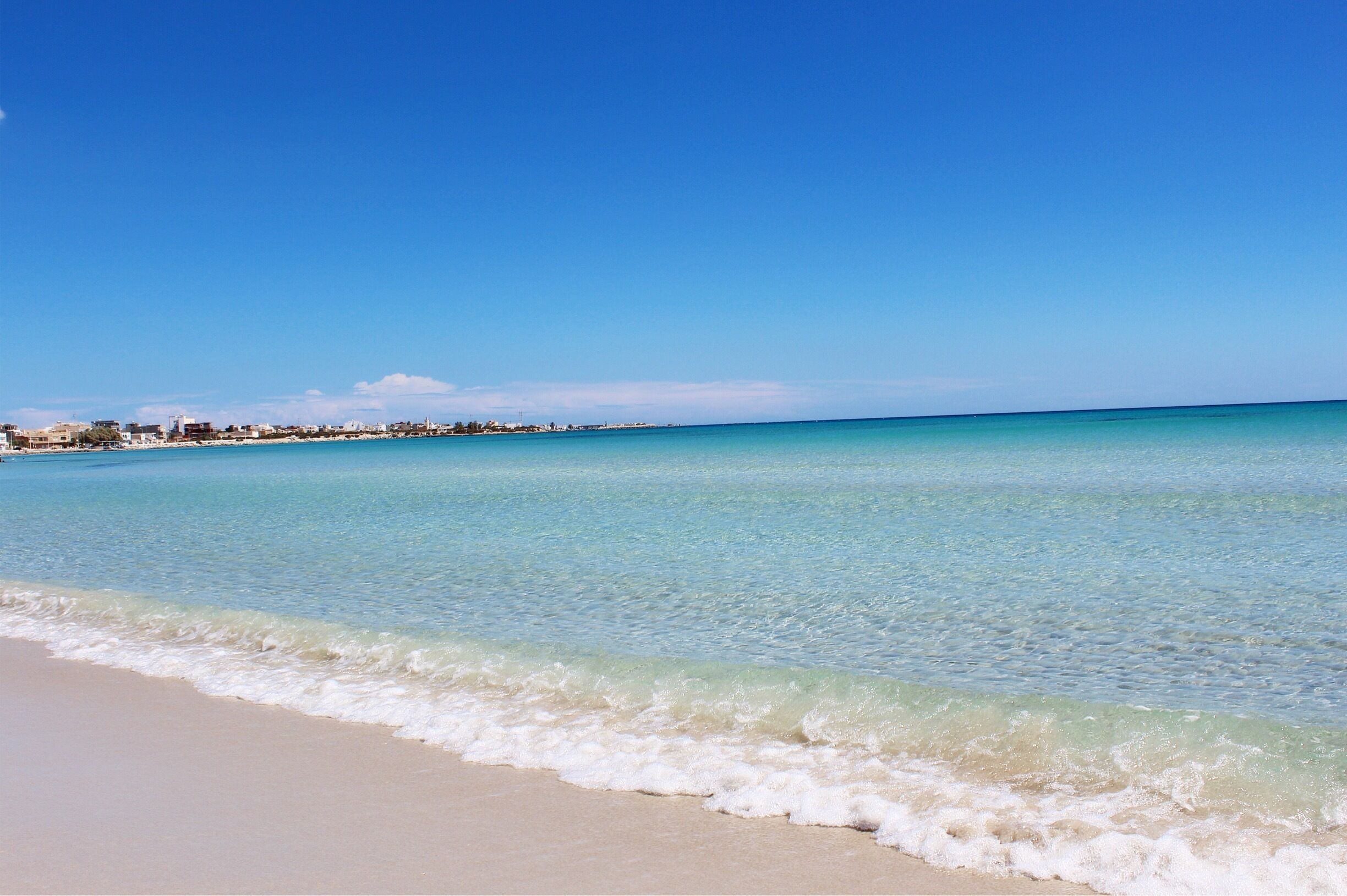 A beach with clear turquoise water and a sandy shore.