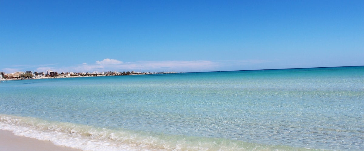 A beach with clear turquoise water and a sandy shore.