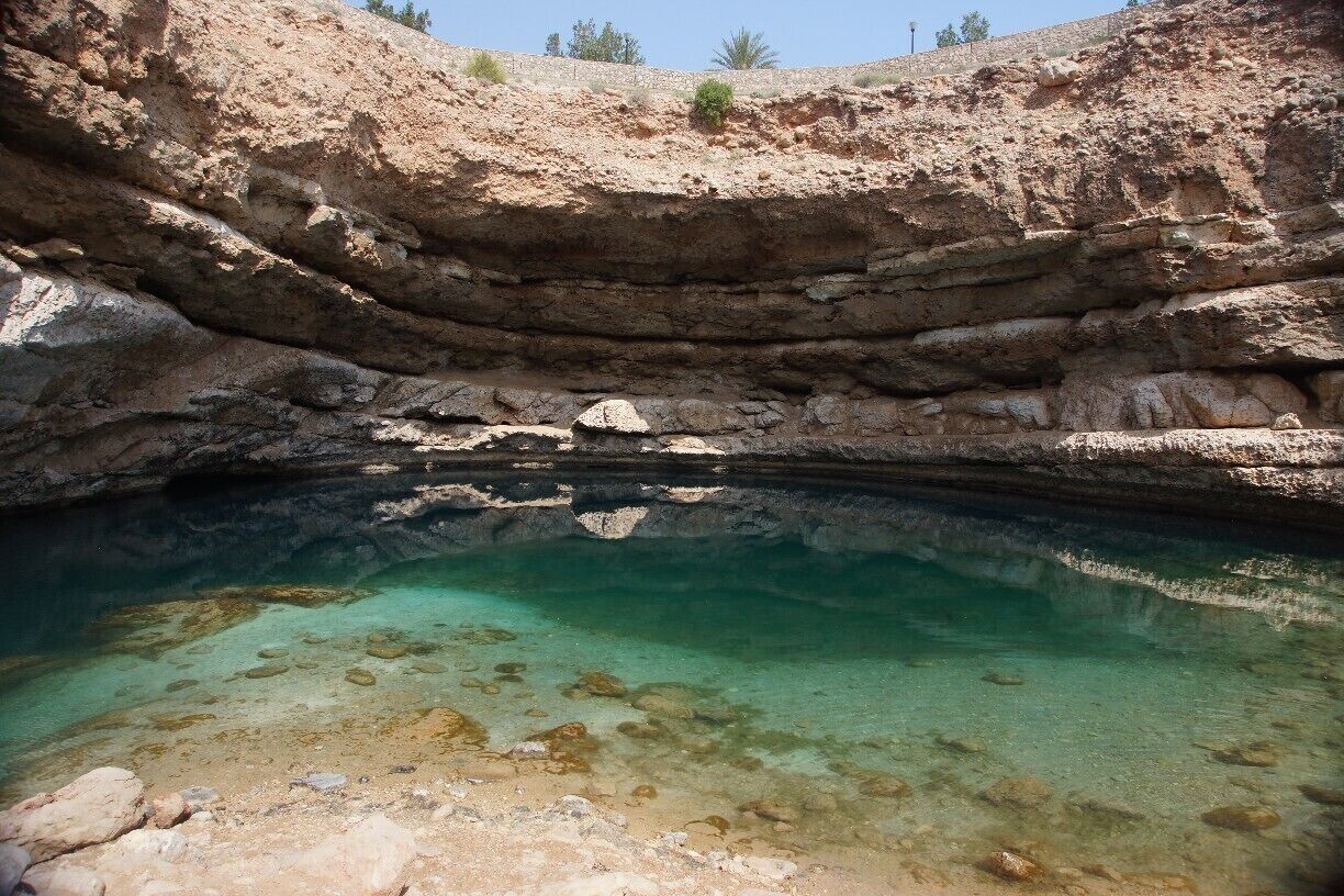 Bimmah Sinkhole is clearly marked on any decent map of Oman, clearly signposted off the highway & thereafter and you do not require a 4WD to get to it.  That being said, every time I go there, I think I have missed the turn and take a dirt track that you should not take in a normal car, only to realise that if I had stayed on the tarmac, the turnoff was just a bit further up the road!  It takes about an hour from Muscat.

There are pan toilets here which double as changing areas.  There are a few picnic spots as well.

To get to the water, you have to go down a lot of steps!  The water is mildly salty and very clear.  The shallows have those tiny fish that eat the dead skin off your feet and legs (free foot spa) and the deeper area is deep enough for jumping off the rocks into the Sinkhole - which plenty of people do.  There are a variety of heights to jump from!

This is one of the first places I visited in Oman many moons ago and it is still a favourite.  The surrounding scenery does not disappoint either as it is perched between the mountains and the sea.