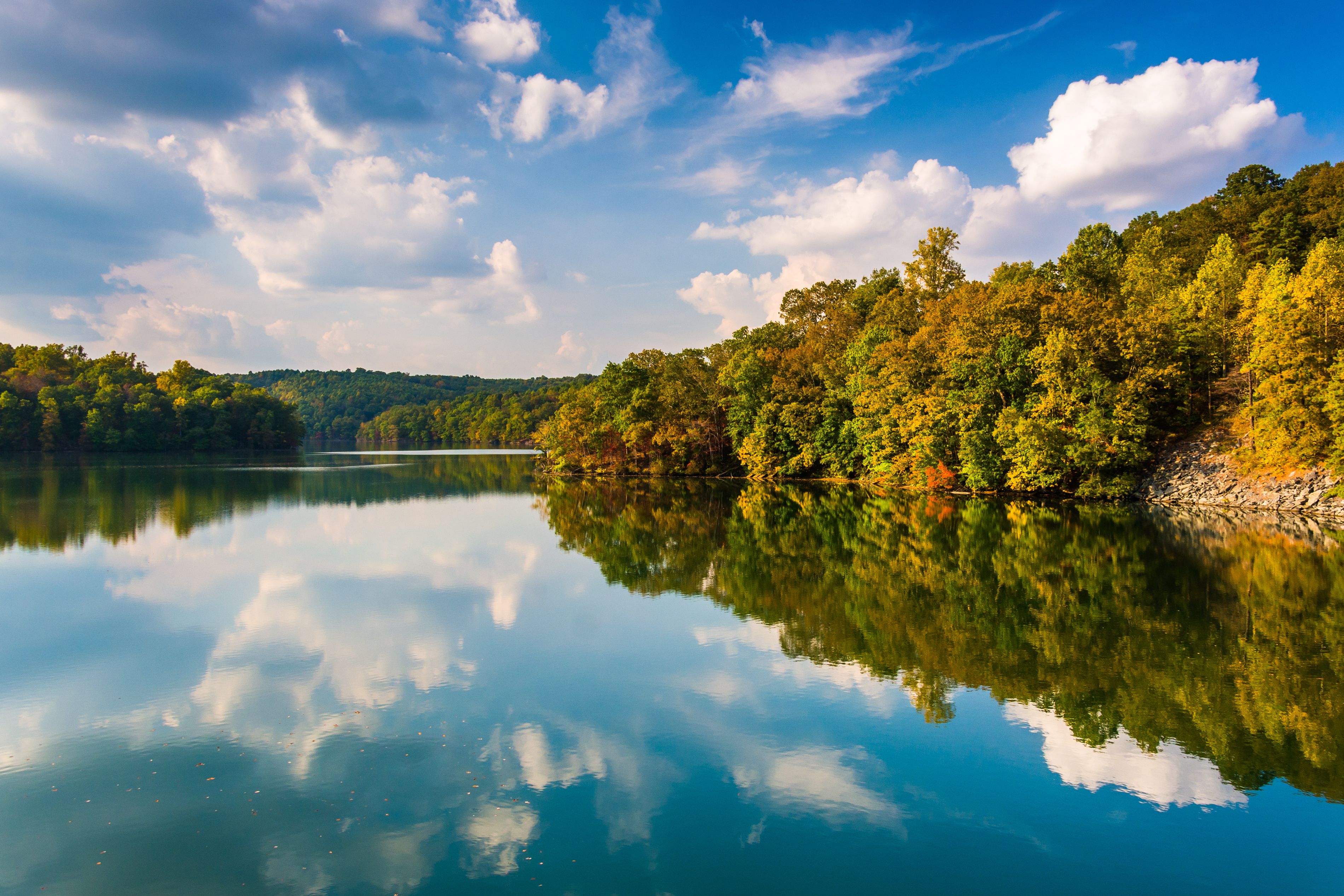 A calm lake reflecting the surrounding trees and sky.