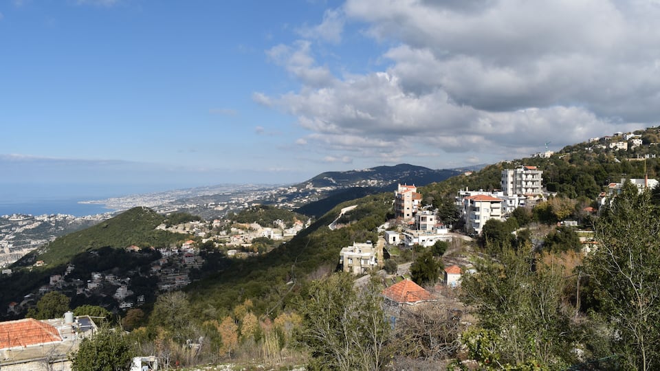 A coastal town with buildings on a hillside, a clear sky, and a view of the sea.