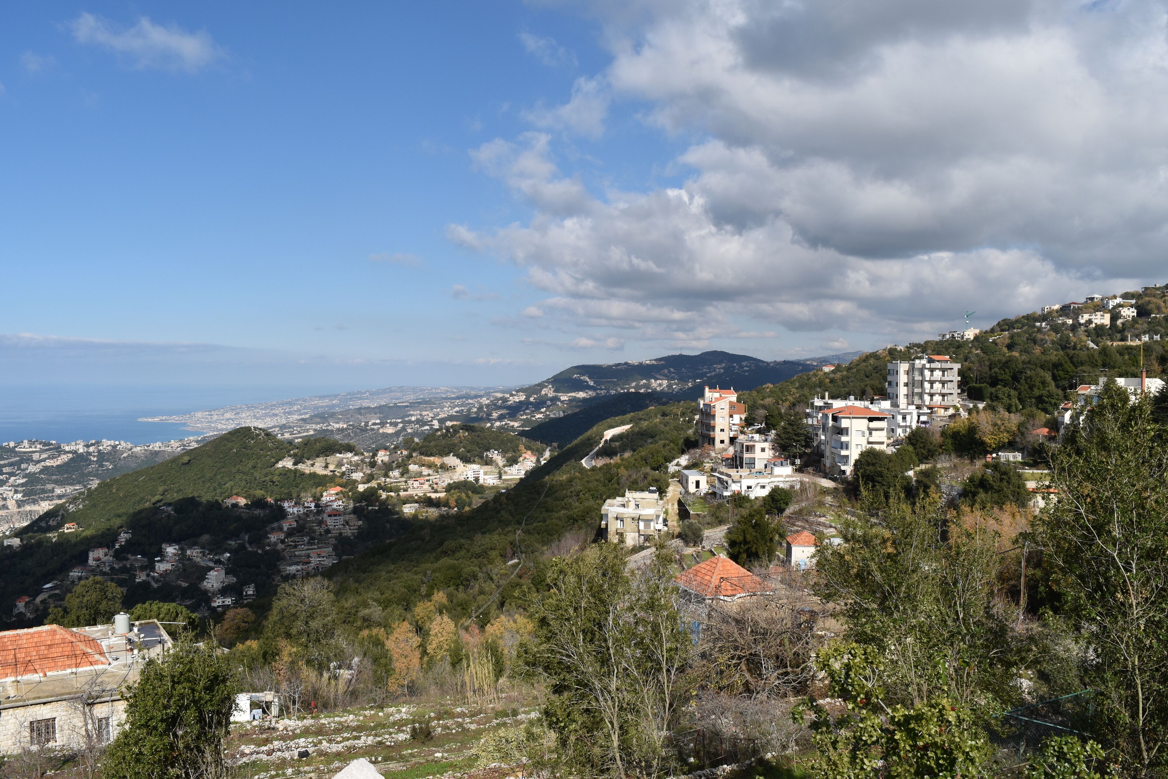 A coastal town with buildings on a hillside, a clear sky, and a view of the sea.