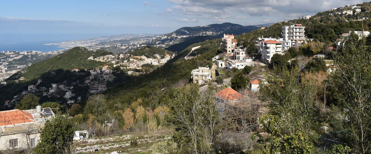 A coastal town with buildings on a hillside, a clear sky, and a view of the sea.