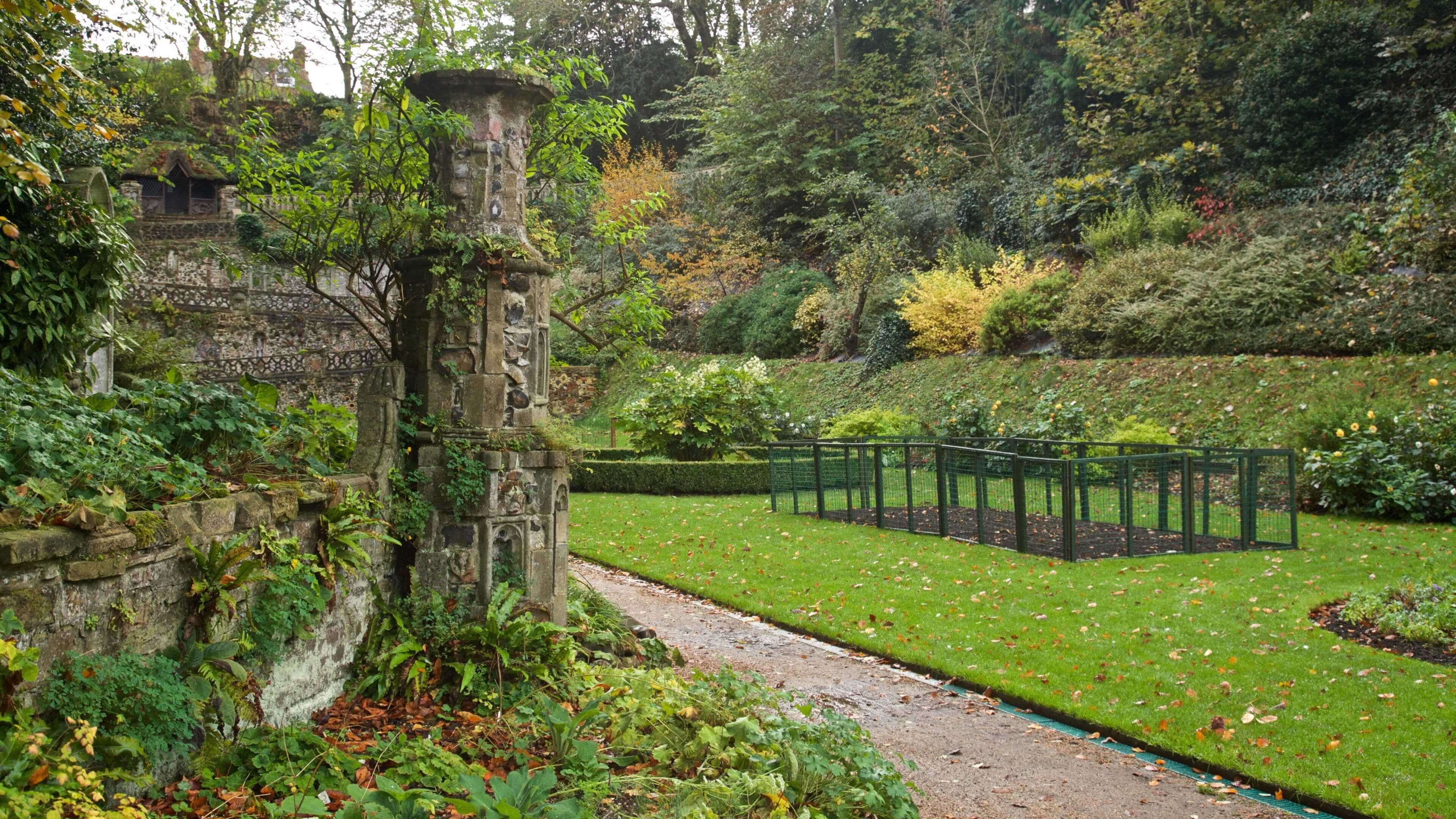 A historic stone structure surrounded by lush greenery and a well-maintained garden.