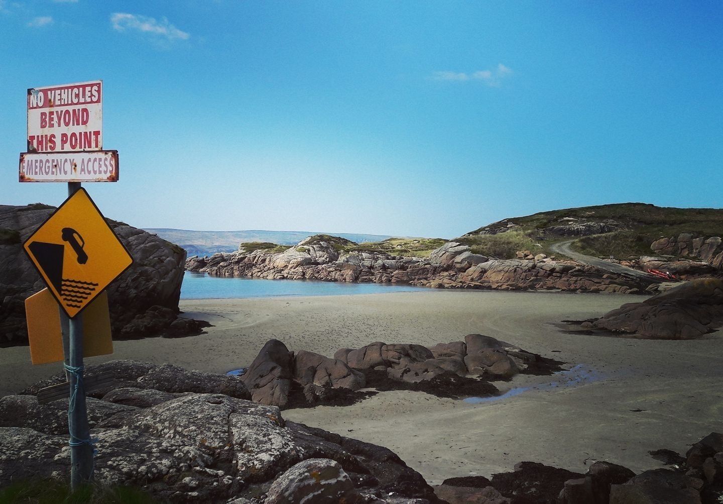 A beach with a warning sign for no vehicles beyond a certain point and emergency access.