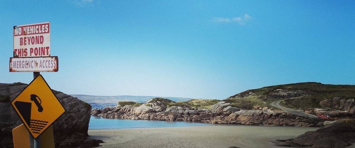 A beach with a warning sign for no vehicles beyond a certain point and emergency access.