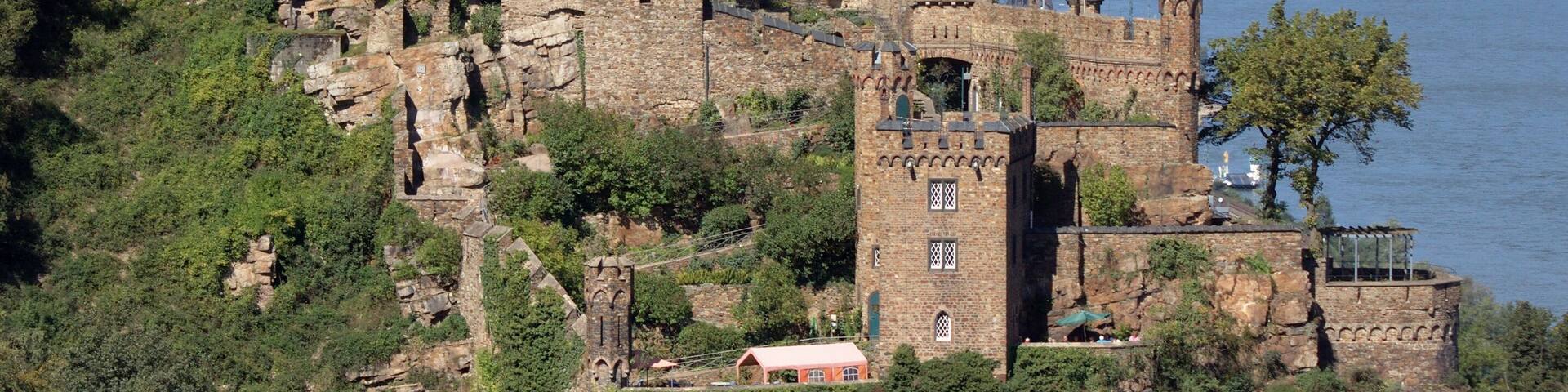 A historic castle on a hill overlooking a river, with a town in the background.