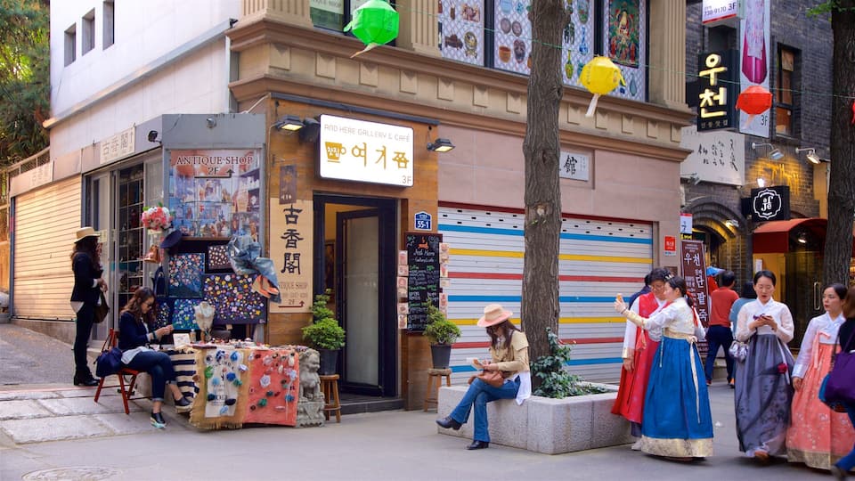 A street with a shop displaying colorful items and a sign for an antique shop.