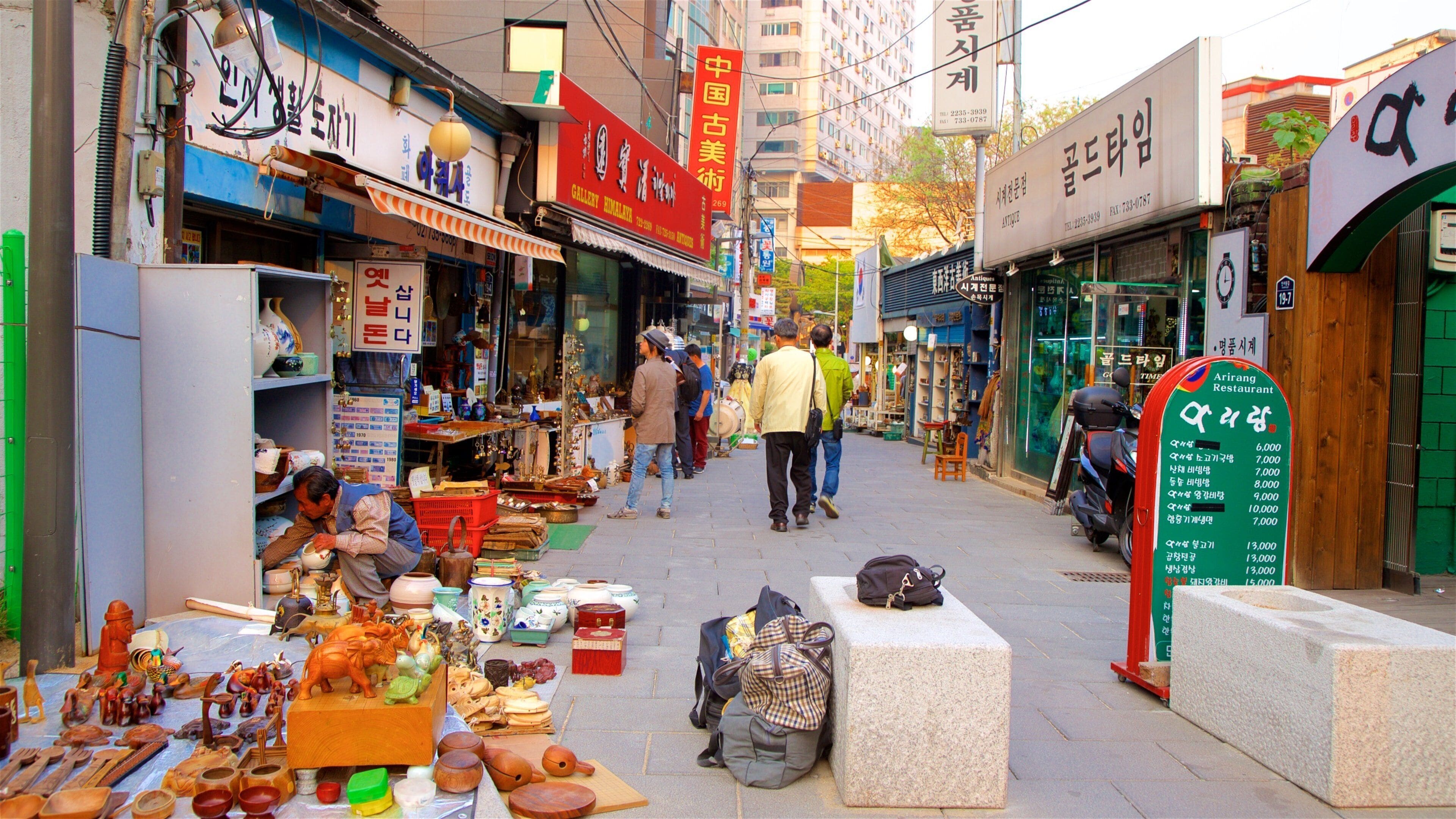 A bustling street market with various shops and stalls selling pottery and antiques.