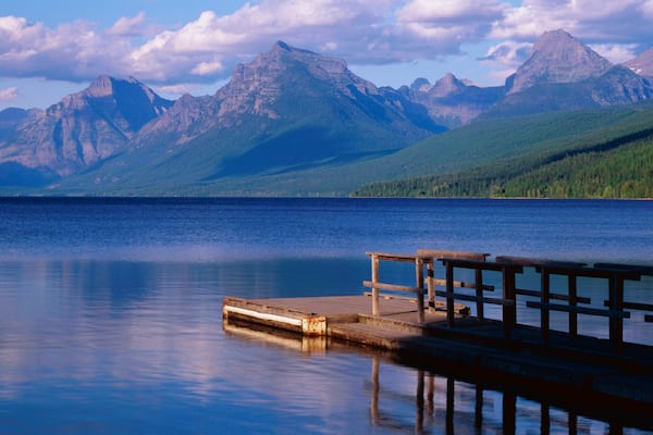 This is a boat dock at Lake McDonald. The blue water of the lake surrounds the dock with mountains in the background.