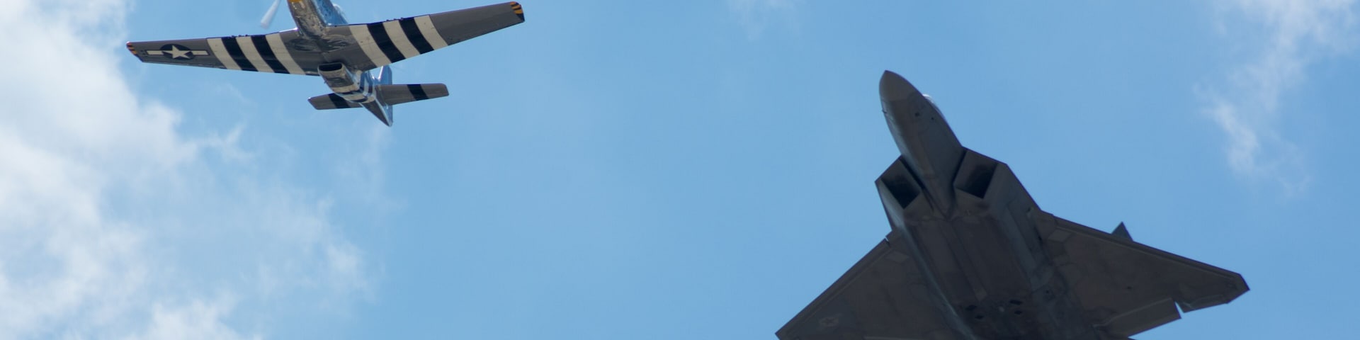 Two military aircraft flying in formation against a clear blue sky.