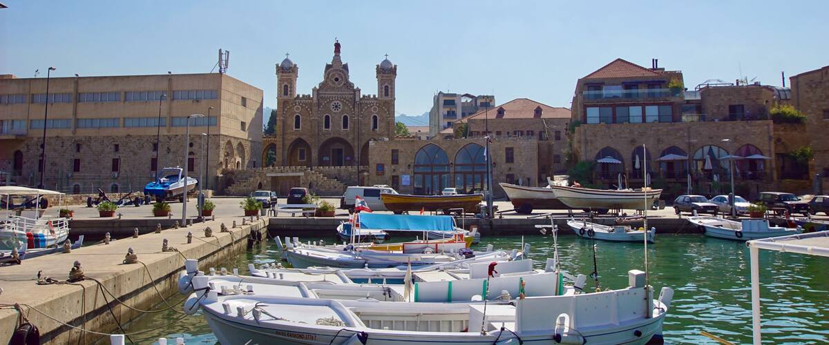 A harbor with boats docked, a historic church, and modern buildings.