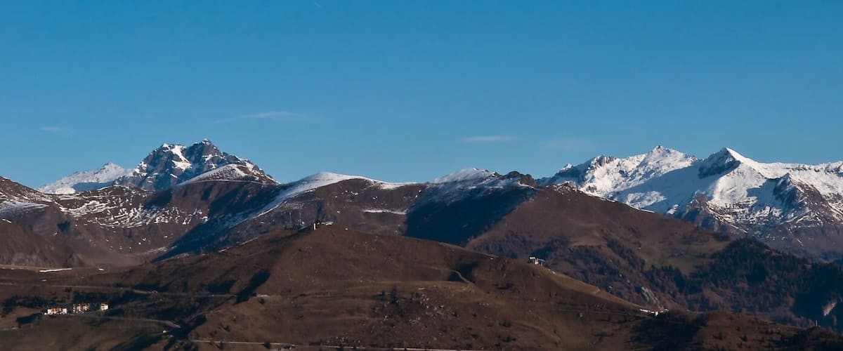 A mountain range with snow-capped peaks and a clear blue sky.