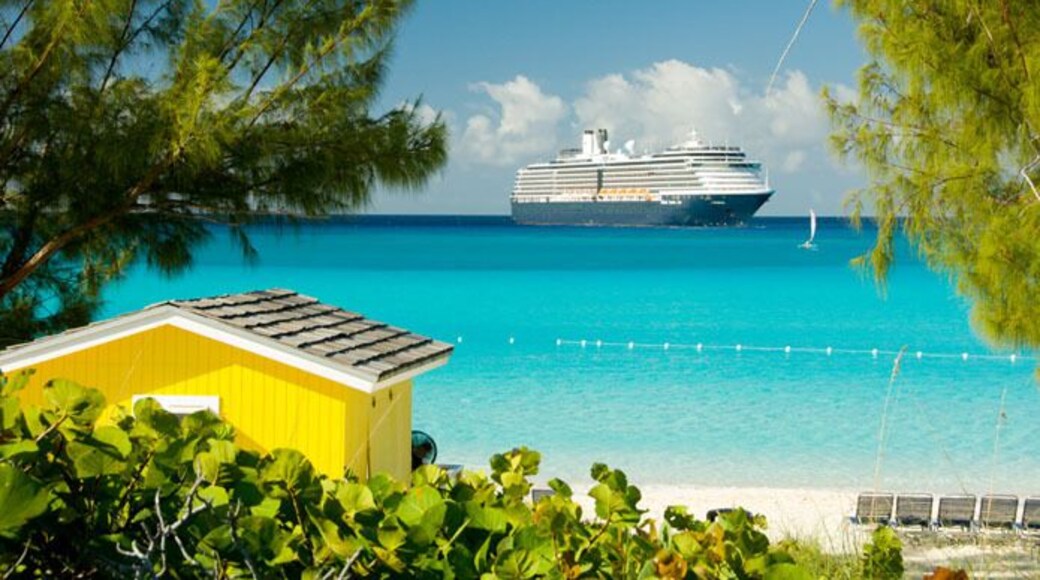 A colorful yellow beach cabana with the Holland America cruise ship Westerdam anchored off Half Moon Cay Bahamas