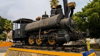 Una locomotora de vapor antigua con la inscripción "Compagnie du Boleo", mostrada sobre una vía con una plataforma amarilla y azul.