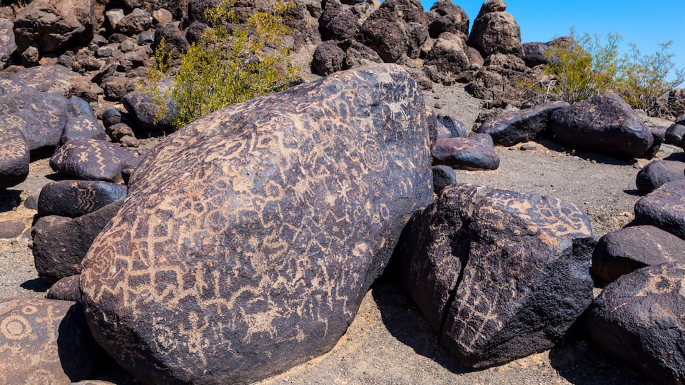 Large boulders with petroglyphs in a rocky terrain.