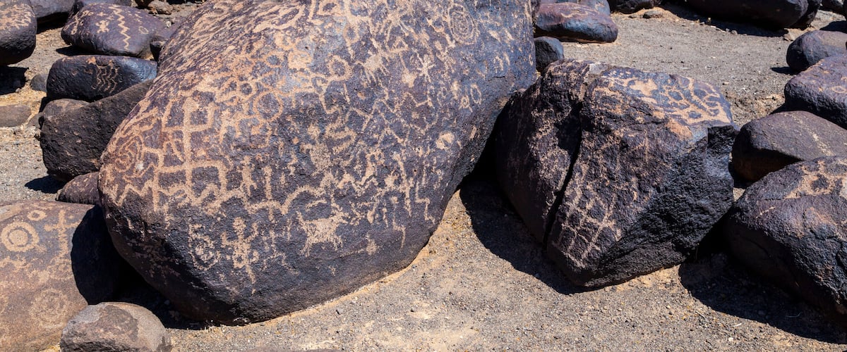 Large boulders with petroglyphs in a rocky terrain.