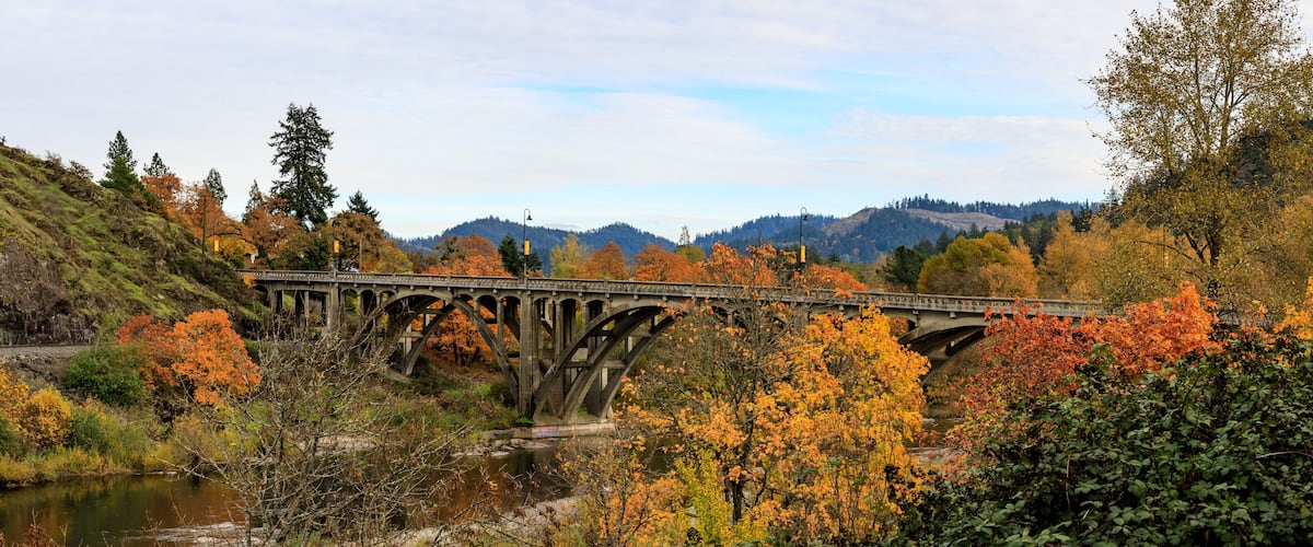 A stone bridge over a river surrounded by autumn foliage.
