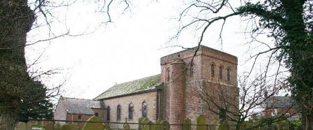 A church with a tall tower and a cemetery in the foreground.