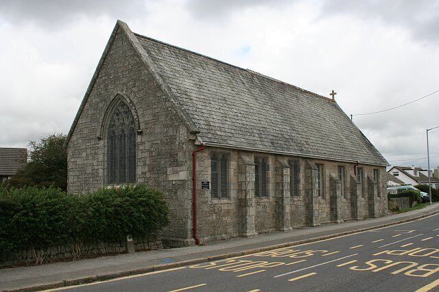 A stone church with a steep roof and a large arched window.
