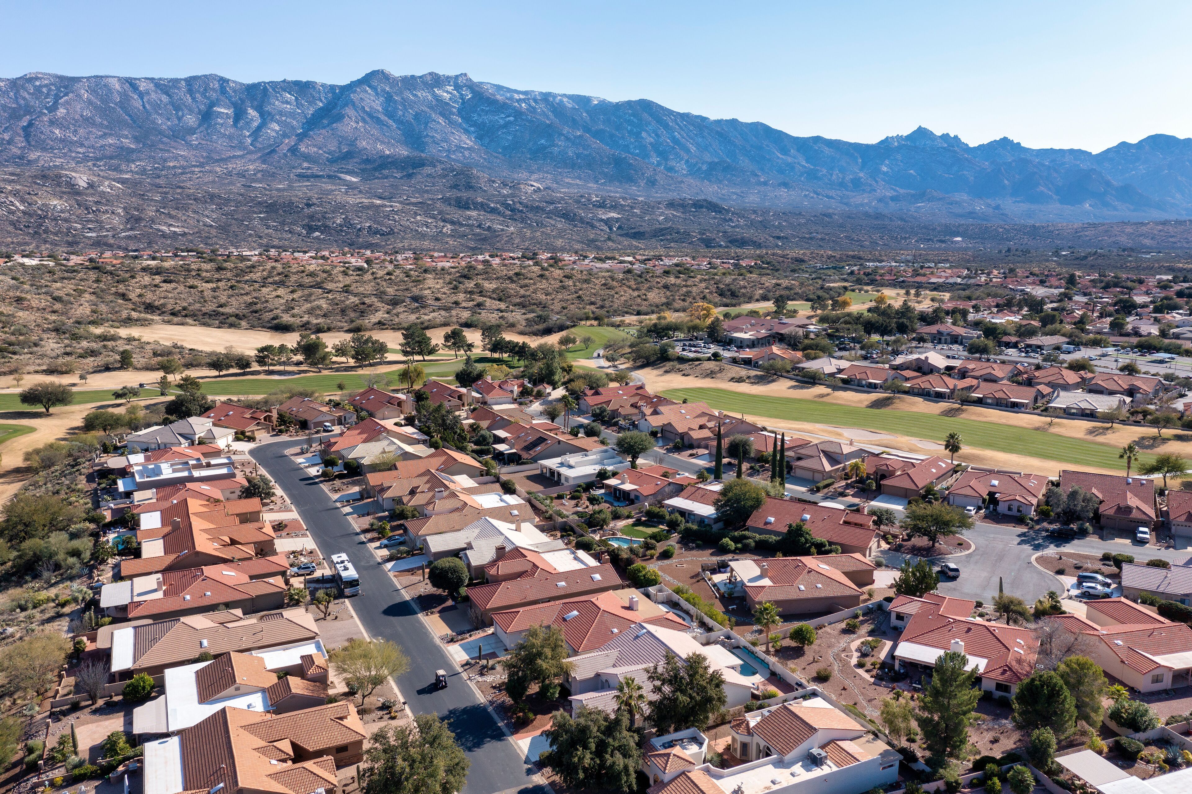 A residential area with houses, roads, and mountains in the background.