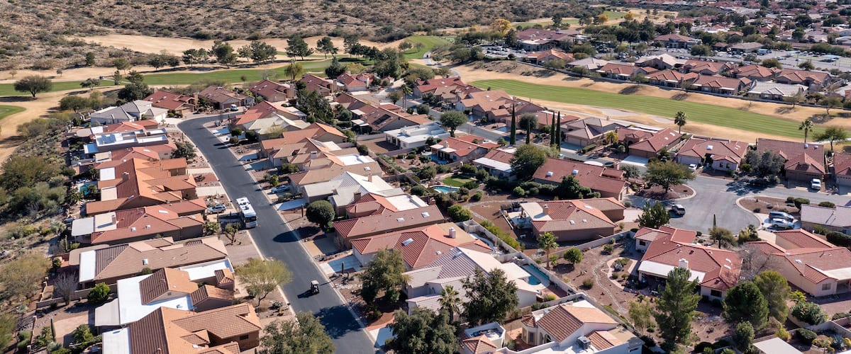 A residential area with houses, roads, and mountains in the background.