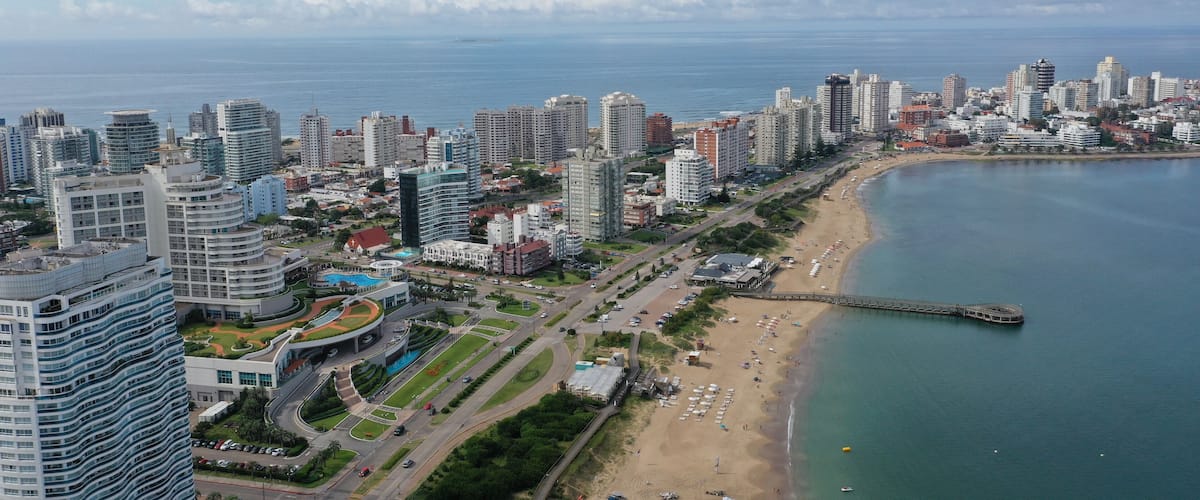 A coastal cityscape with high-rise buildings, a beach, and a calm sea.