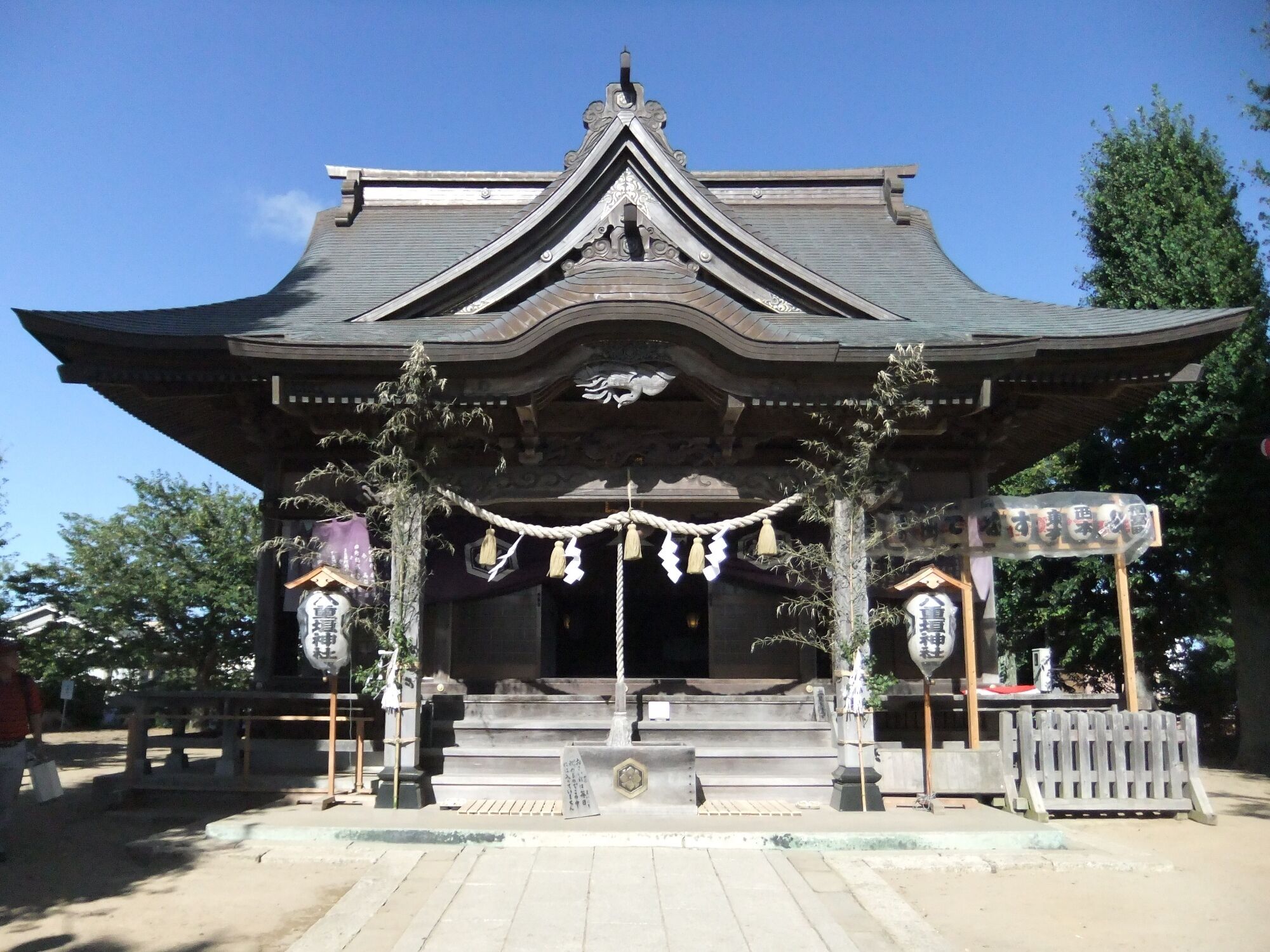 A traditional Japanese temple with a curved roof, wooden beams, and hanging decorations.