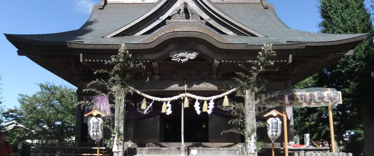 A traditional Japanese temple with a curved roof, wooden beams, and hanging decorations.