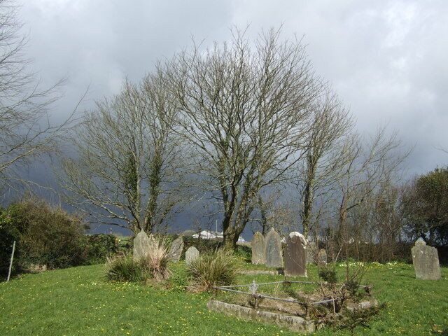 A cemetery with headstones and leafless trees.