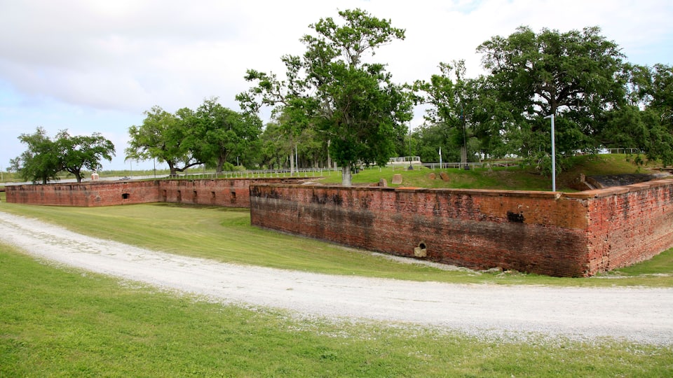 A historic brick fort with surrounding grassy areas and trees.