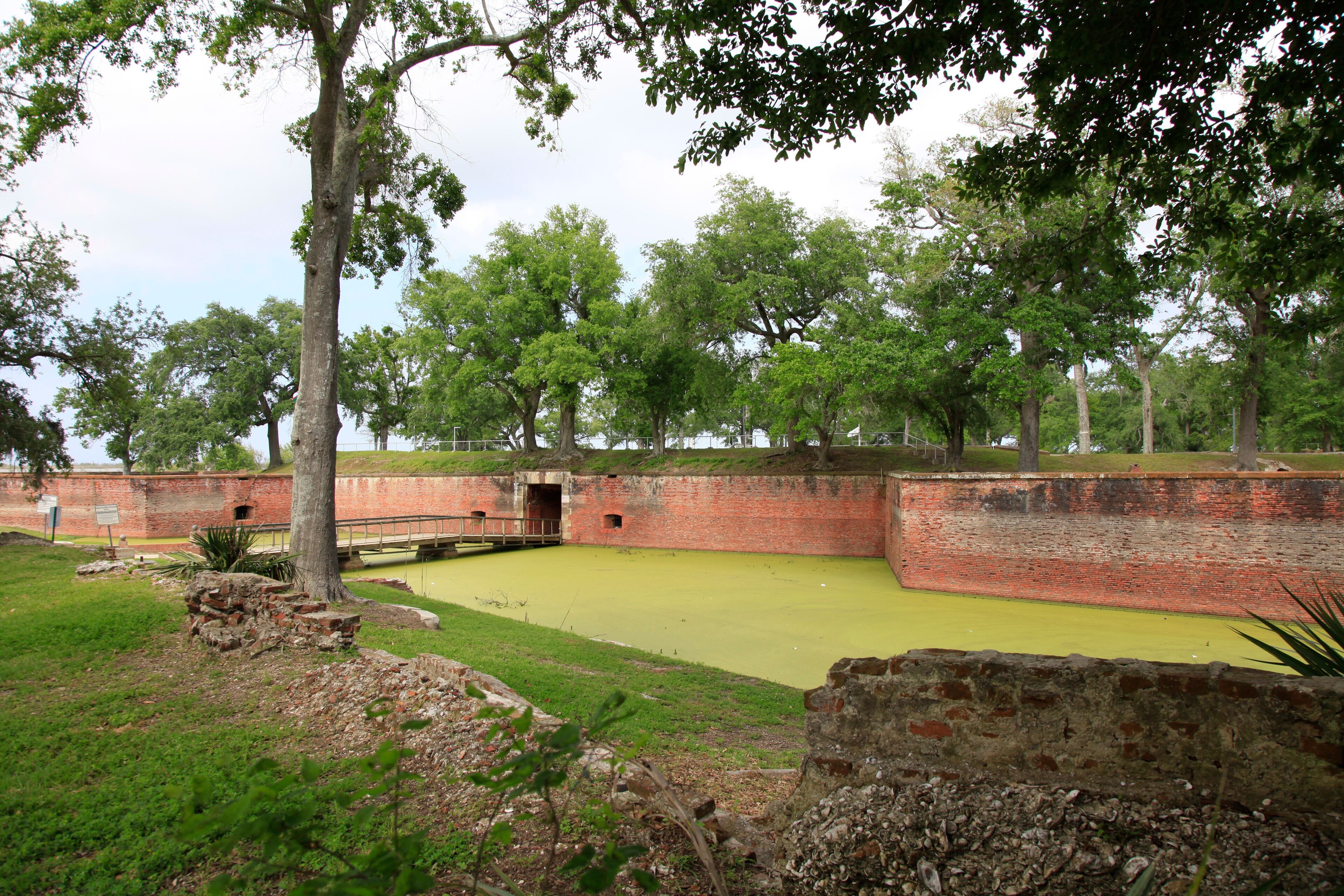 A historic brick fort with green grass and trees.