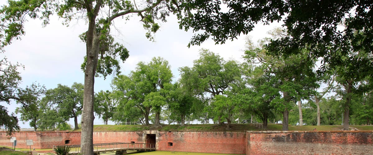 A historic brick fort with green grass and trees.