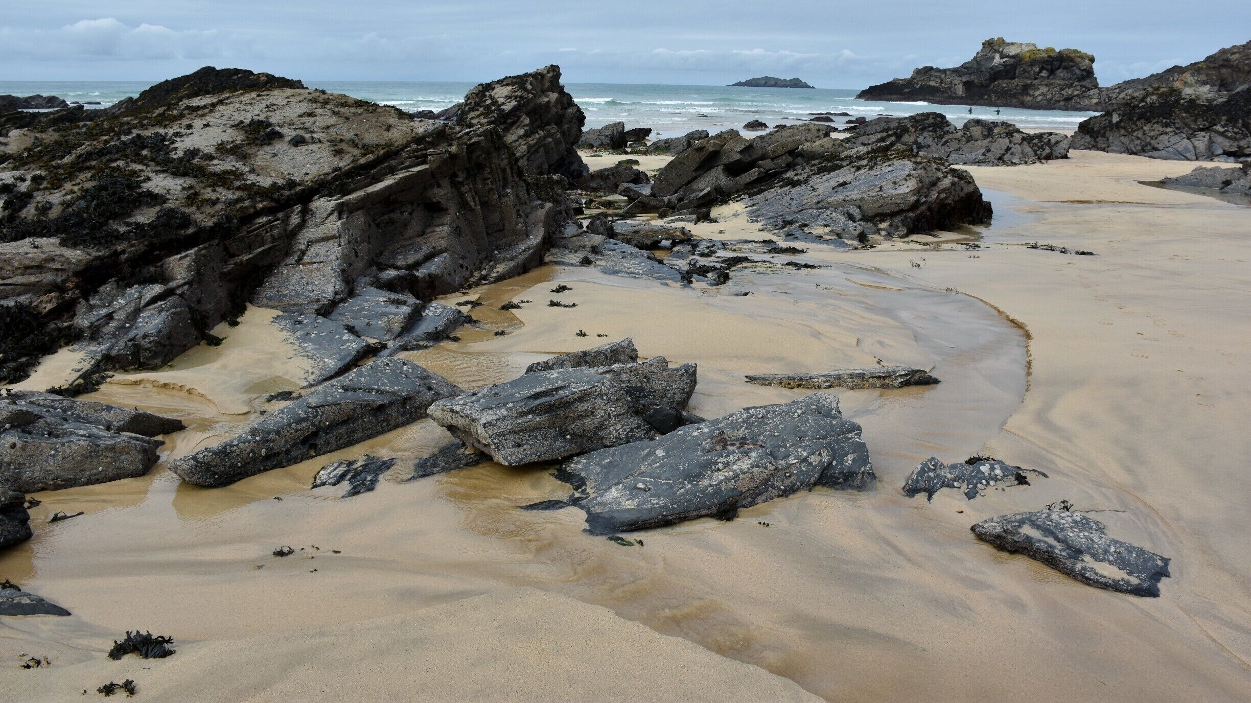 A rocky beach with large boulders and a sandy shoreline.