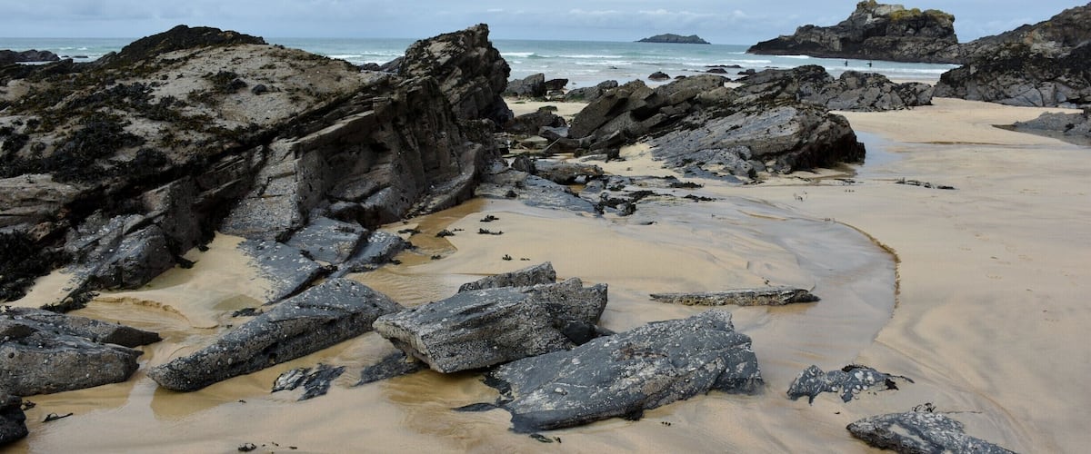 A rocky beach with large boulders and a sandy shoreline.