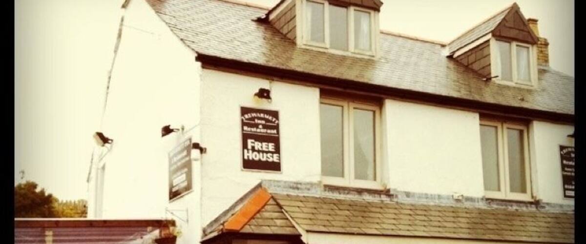 A white building with a sign that reads "FREE HOUSE" and a sign that says "OPEN" on the side.