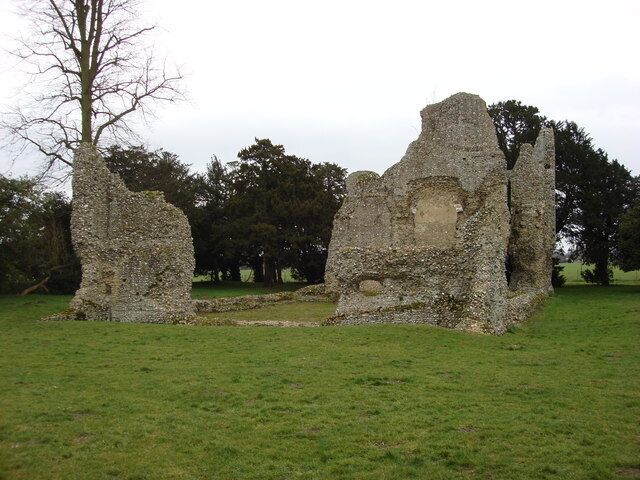 A stone ruin with two large pillars and a central archway in a grassy field.