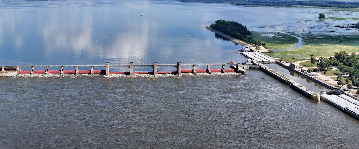A dam with a lock system, surrounded by water and greenery.