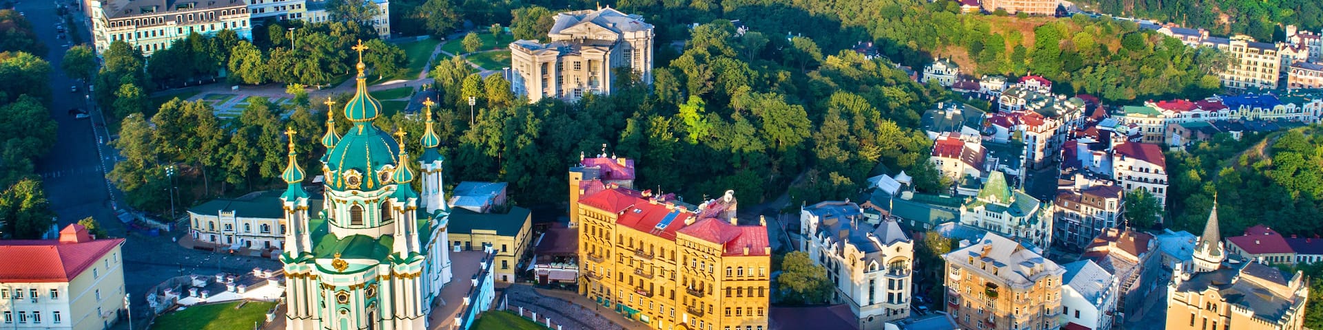 A cityscape with a prominent green-domed cathedral, surrounding buildings, and a dense urban area in the background.
