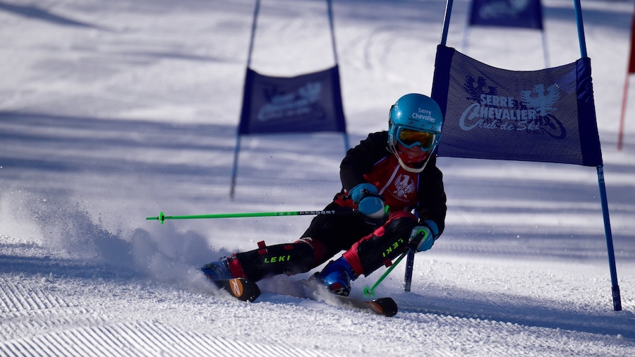 A skier in motion on a snowy slope with flags and a logo.